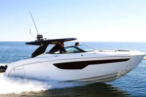 White motorboat speeding across open water with two people in the cockpit and a wake behind it.