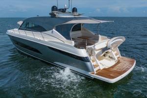 White luxury motor yacht on blue water with teak aft deck and open cockpit area