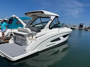 White motor yacht docked at a marina under a clear blue sky, with a man in a turquoise shirt stepping onto the dock nearby.
